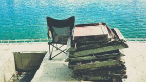 A chair beside a stack of concrete by the lakeside