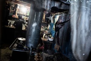 Hector Vargas and his son. Hector cleans the skin of the recently slaughtered cow to use it in order to make ropes for saddles and horses while his son cuts parts of the meat inside the house.