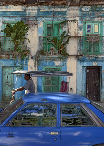 A tricycle taxi rides past a colourful facade in the La Habana Vieja district of old Havana.