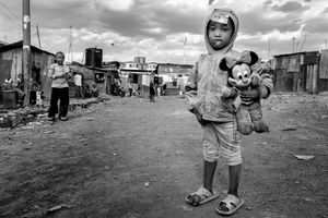 © Tony Corocher - Western beauty in Nairobi's hell (Kibera Slum - Nairobi) - This little girls caught my eye because of a really strong contrast … she was holding a classic symbol of western beauty inside one of the harshest realities in the world.