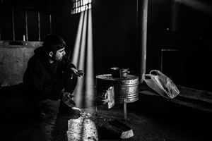 Man makes tea on the makeshift stove and tries to warm himself inside a derelict warehouse in Belgrad, Serbia.