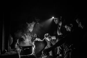 Migrants cooking food on the fire. Inside derelict warehouse in Belgrade, Serbia.