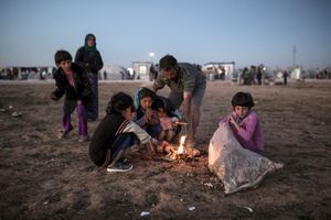 Syrian Kurdish refugees try to get warm around a fire at 'Arin Mirhan' refugee camp in the town of Suruc, Sanliurfa province, Turkey on November 7, 2014.