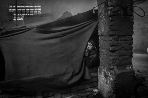 A young boy wakes up in his tent inside the barracks