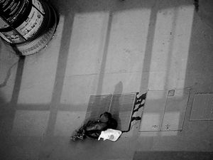 Persona sin techo, durmiendo sobre una salida de aire caliente