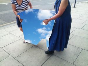 Two ladies carrying a piece of sky together.