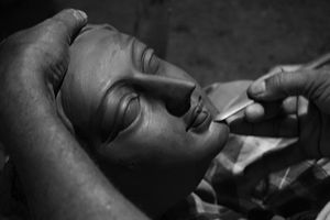 Artisan giving shape to the face made up of clay.