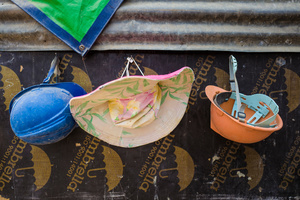 A woman's sun hat hangs between two hard hats.