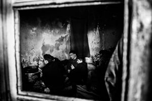 Man during cooking. View through a window into one of the "rooms" in abandoned warehouse in Belgrad, Serbia.