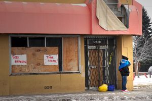 © Nicholas Gregory.     A teenage boy waits near signs that promote the value of education in a city where high school graduation rates are among the lowest in the nation. One quarter of Detroit residents age 25 and older do not have a high school diploma.
