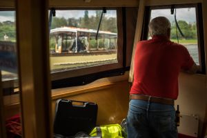View from the bow of a sightseeing canal boat. The man is spotting for a man steering the boat at the stern.