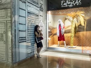 A girl hanging out in a shopping center in front of a window of the luxury store Galeries LaFayette during Ramadan.