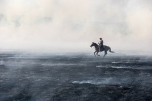 Rancher riding through smoke