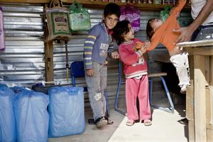 A father and his three children in the family's food shop in Zaatari's main street. © Tom Verbruggen