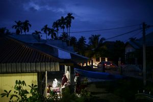 A survivor pray after evening prayer outside of her house as she traumatized to not be in the house following the earthquake in Pidie Jaya, Aceh province, on December 11, 2016.
