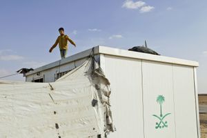 A boy standing on the roof of his container home, trying to capture a pigeon. © Tom Verbruggen