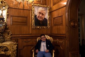 A guest poses in the hall of “Grand Hotel La Sonrisa”, below the photo of Mario Merola, a very famous singer from Naples in the 70's.
