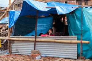 Beneath hastily assembled tarpaulins, a woman takes shelter after her family home was destroyed by the 2015 Nepal earthquake.