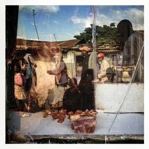 A street scene reflected in the window of a butcher's in Kibera. The Kibera slum is the largest slum in Nairobi with around half a million inhabitants.