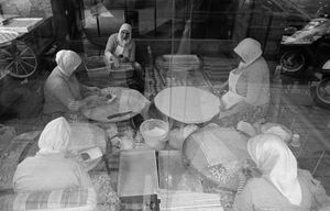 Women seen through a restaurant window, make Gozleme, thin layers of dough filled with cheese, meat or vegetables and toasted on a convex grill.