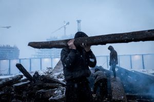 The boy from Afghanistan carries the wood to the warehouse