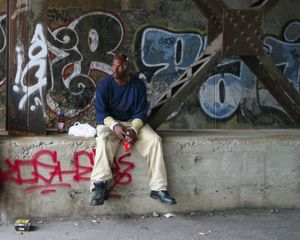 An hourly worker sits outside the New Center Stamping Plant on Hastings Street. As the only operating factory in the area, the desolate location includes workers milling about and little else. Once the main corridor of Paradise Valley, most of the street was demolished for urban renewal. Famous blues musician John Lee Hooker referenced the wild Hastings Street scene in his songs.© Nicholas Gregory