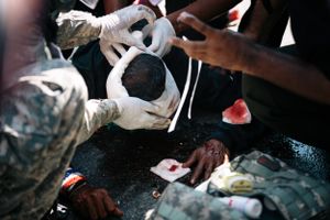 A protester injured when police fired tear gas canisters receives treatment from medical staff during a stand-off between anti-Government protesters and police at Government House in Bangkok.