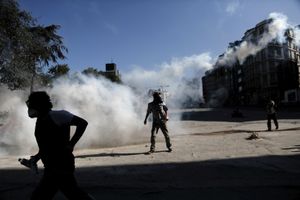 A protester has just thrown back to police a tear gas canister as an other trying to cover after riot police fire tear gas to disperse the crowd during clashes near Taksim square in Istanbul, Tuesday, June 11, 2013.