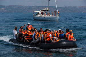 An inflatable boat carrying some fifty Syrian refugees approaches the shore on the northeastern part of Lesvos escorted by a sailing boat in case help was needed. More than 30,000 refugees have reached the Greek island of Lesvos during August 2015, according to Amnesty International.  August 25, 2015, Lesvos, Greece