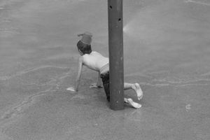 Jeux d`enfant.Le petit garcon avec un arrosoir sur la tête.