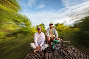 Two drivers of bamboo train, or Norry, speed along the railway track.