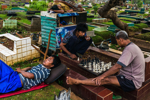 Care takers play chess over one of the tombs at Karet Bivat cemetery