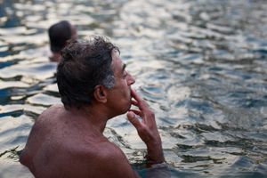Man is enjoying his cigarette while swimming