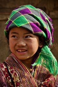 Young girl from the H'mong minority wearing a bright patterned headscarf and detailed colourful jacket.