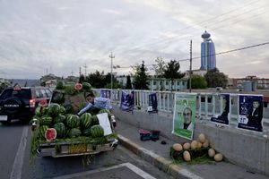 A man selling water melons from the back of his pick up truck, with the Grand Millennium Hotel tower in the background in the city of Slemani. © Tom Verbruggen