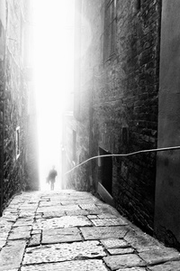 The rising sun begins to burn the morning mist from alleyways
