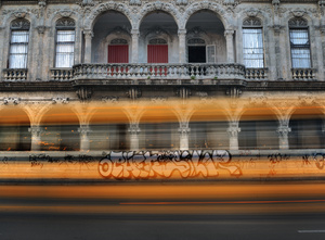 A school bus rides past a old Havana facade.