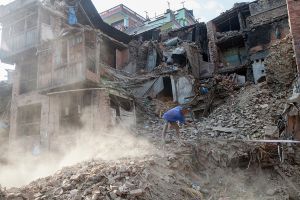 A man clears rubble and collects items from his destroyed home in Bhaktapur, Nepal.