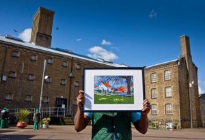 A member of the prison art club holds up one of his paintings. HMP Wandsworth, London, United Kingdom
