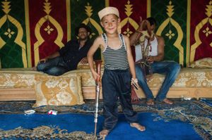 A young Moroccan boy poses with a child sized musket inside the traditional cherifian tent , during down time for the riding teams