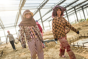 Tob Soav 45 and  Sok Chan 38 carry a basket of soil under the shell of a large warehouse construction.