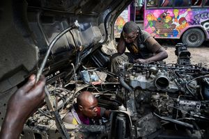 Nairobi, September 27, 2019. Mechanics in a garage in Buru Buru Phase 1 fix the engine of a Matatu, while Scooby Doo & Co. seem to watch them with a certain surprise and astonishment. . The mechanics earn about 150 USD a month, which is about ten percent of the average monthly profit which an owner usually makes with one Matatu after paying all expenses including the bribes for the traffic police.