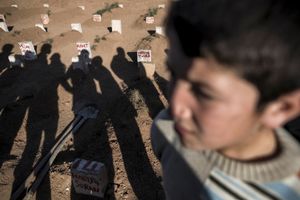 A Kurdish boy stands in front of graves of Kurdish fighters during a funeral of People's Protection Units (YPG) and Kurdish Women's Protection Unit (YPJ) fighters in Suruc, Turkey on November 7, 2014.