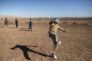 A Syrian Kurdish children play football outside of the 'Arin Mirhan' refugee campi in the border town of Suruc, Sanliurfa province, Turkey on November 5, 2014.