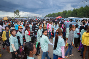 Workers buy food in front of the factory at the end of their shift.