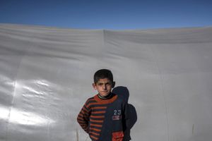 A Syrian Kurdish boy poses for a photo in front of a tent at 'Arin Mirhan' refugee camp in the border town of Suruc, Sanliurfa province on November 5, 2014.