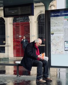Paris, older man on bench, younger man smokes in doorway
