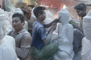 Labourers grinding statues of Buddha at workshop in Mandalay.