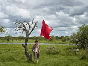 Gauchito Gil devotee holding an image of the popular saint while fling the red flag in the El Yaguarì estancia in Curuzù Cuatià village