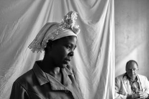 This young woman awaits a second opinion about her child, a referral from the first doctor to a pediatrician, their offices and examining rooms separated by this draped bed sheet.                                   © Lola Reid Allin
